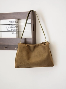 Detail of a brown suede Boston bag with olive green straps and antique bronze hardware