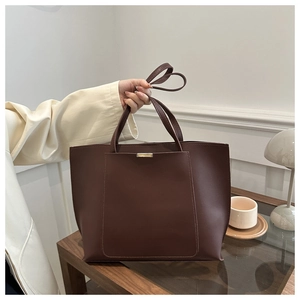 Detail view of large dark coffee tote bag with matte leather texture and gold hardware accents