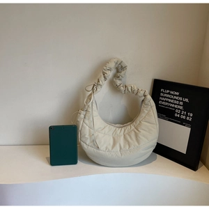 Detail of cream quilted half-moon bag featuring cloud-style pleated handle and soft texture
