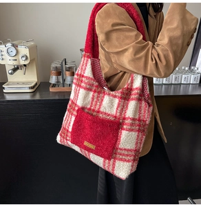 Detail of red and white plaid plush tote bag with yellow label and warm fleece texture