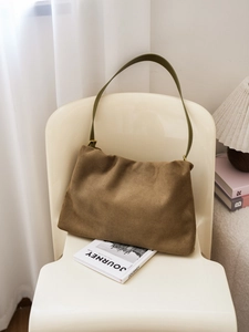 Close-up of brown suede Boston bag on a chair showing premium texture and long straps