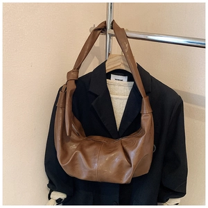 Detail of the knotted shoulder strap and soft leather texture on a brown hobo bag