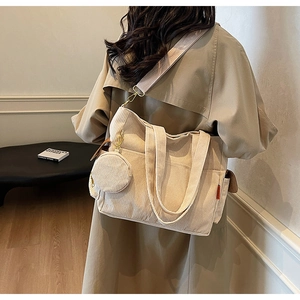 Detail of beige corduroy tote bag featuring a matching round coin purse and textured fabric