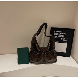 Detail der dunkelbraunen Hobo-Tasche zeigt Kapazität für ein grünes Tablet