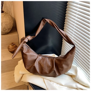 Detail shot of the pleated texture and knotted shoulder strap on the brown PU hobo bag