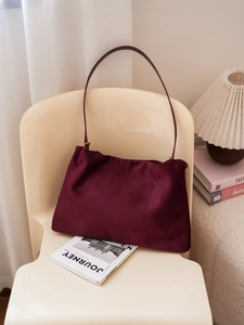 Close-up of deep burgundy suede Boston bag with minimalist shoulder strap and matte texture