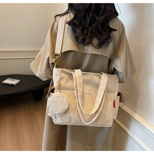 Detail of off-white corduroy tote bag with adjustable shoulder strap and small coin purse