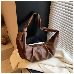 Close-up of retro dark brown hobo bag with knotted strap details on white fabric