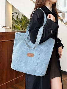 Minimalist light blue canvas tote bag with brown leather label worn by a model