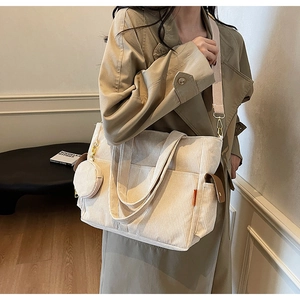Detail of beige corduroy tote bag with side pockets and a small round detachable coin purse