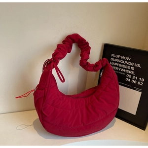 Detail of red quilted puffer bag showing ruffled handles and soft nylon texture