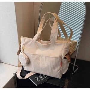 Detailed shot of off-white corduroy tote bag with adjustable strap and small round coin purse