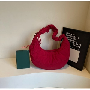 Detail of red quilted puffer shoulder bag with ruched strap and soft nylon texture