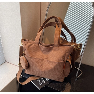 Detail view of brown corduroy tote with adjustable strap and small round coin purse
