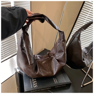 Detail of coffee brown pleated hobo bag with knotted strap and soft leather texture
