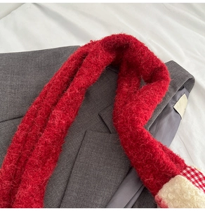 Detail of red plush scarf texture with red plaid patchwork and white fleece trim