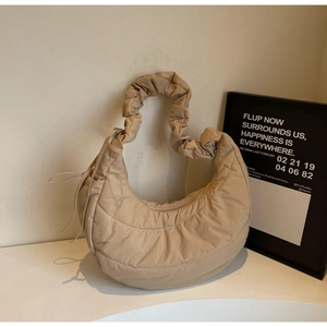 Detail of beige quilted crescent shoulder bag with elegant ruched strap and soft texture