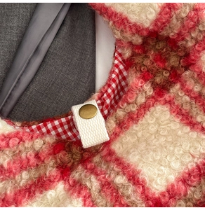 Close-up of red plaid plush bag showing faux shearling texture and gold snap button