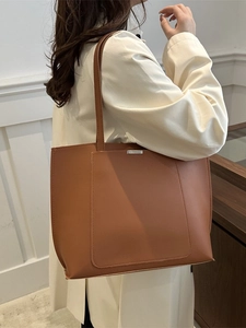 Brown large capacity tote bag with silver metal trim and shoulder straps on a model