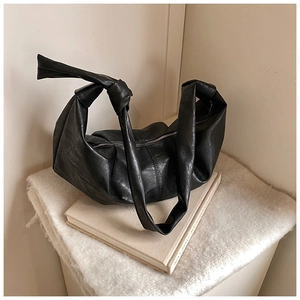 Detail of minimalist black hobo bag showing large knotted handle and soft leather texture