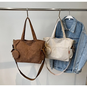 Detail of corduroy tote bags with round pouch charms and side pockets in two colors