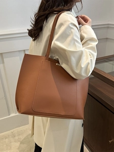Brown large-capacity faux leather tote bag with front pocket shown on shoulder