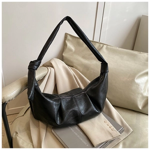 Detail of black faux leather hobo bag featuring soft pleats and a knotted shoulder strap
