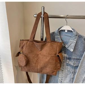 Close-up of brown corduroy tote bag showing large front pocket and mini round coin purse