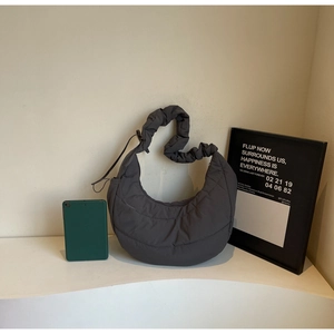 Macro view of dark grey quilted hobo bag with ruffled shoulder strap and tablet capacity
