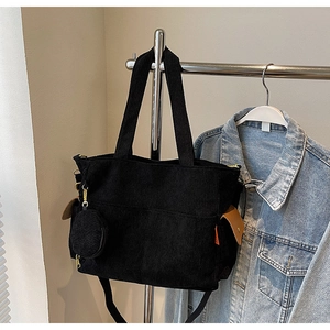 Detail of black corduroy tote bag with mini coin purse and side decorative label