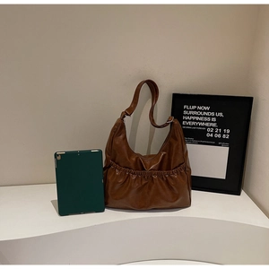 Detail der dunkelbraunen Leder-Hobo-Tasche mit Falten-Taschen und weicher Textur