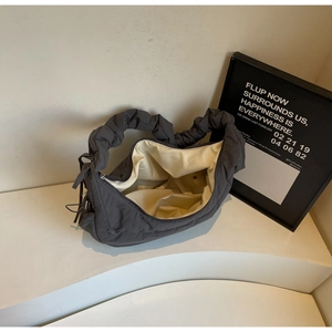 Detail view of charcoal grey down bag showing ruched handle and beige fabric lining texture