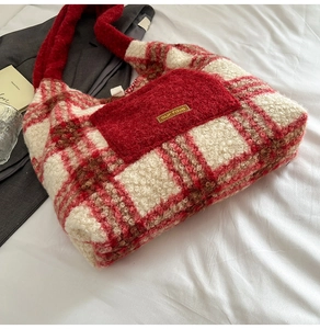 Detail view of red plaid plush tote bag with fuzzy texture and front pocket showing its soft fabric