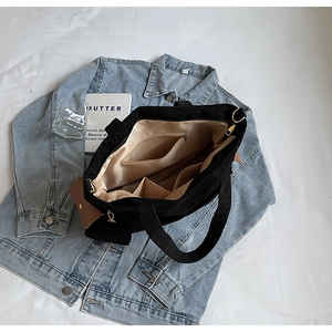 Internal view of the black corduroy tote bag showing beige lining and multi-pockets