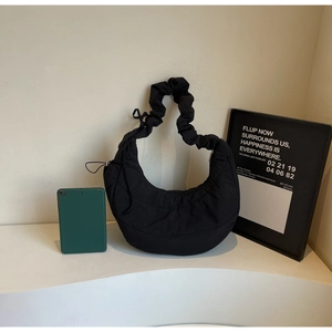 Detailed view of black quilted puffer crescent bag with pleated handle and matte texture