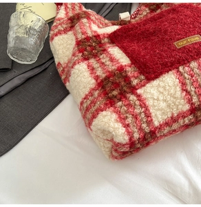 Macro detail of red and white plaid plush tote bag with furry pocket and leather tag