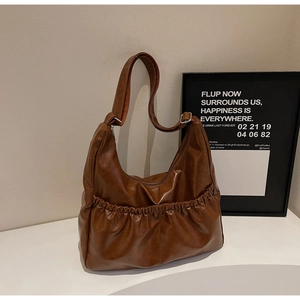 Nahaufnahme der braunen Hobo-Tasche aus PU-Leder mit Falten und verstellbarer Schnalle