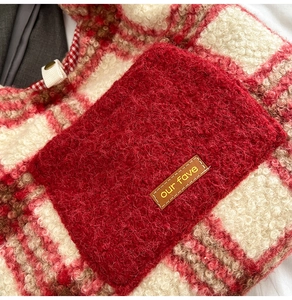 Detail of red plaid faux shearling tote with leather label and textured plush fabric