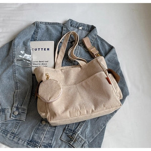 Detail of beige corduroy tote bag with mini round pouch and adjustable strap on denim