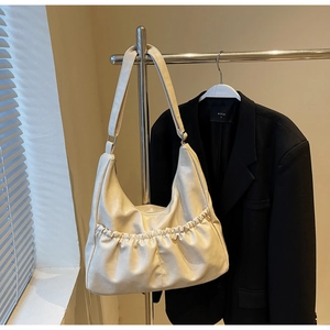 Detail einer cremeweißen Falten-Umhängetasche mit glattem Leder und Reißverschluss