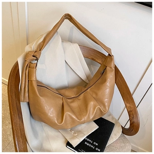 Close-up of camel pleated hobo bag featuring knotted shoulder strap and textured leather