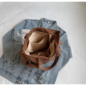 Detail view of large corduroy tote bag showing interior zip pocket and brown texture