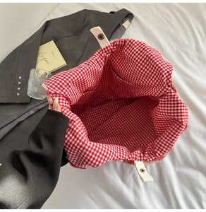 Detail view of red gingham inner lining with storage pocket and golden snap button closure