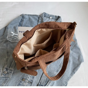 Detail view of the spacious inner lining with zipper pocket of this brown corduroy tote bag
