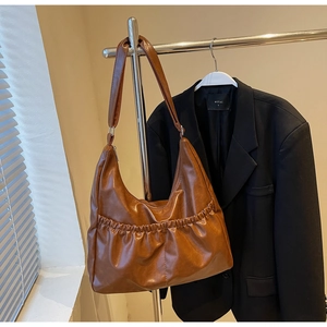 Detailansicht einer braunen Vintage Hobo-Tasche mit Falten aus glänzendem Leder und Gurt