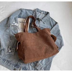 Macro view of brown corduroy tote bag showing side pocket with flap and metal hardware