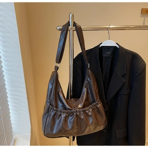 Detail der dunkelbraunen Hobo-Tasche mit Falten vorne und polierter Wachstextur