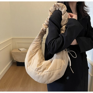 Detail of beige quilted puffer bag featuring soft pleats and a wide ruched shoulder strap