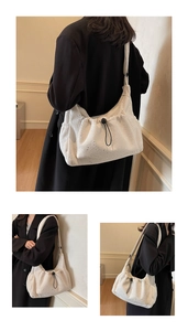 Detail view of white nylon crescent bag showing pleated texture and black drawstring cord