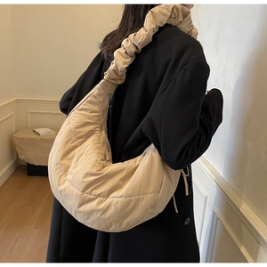 Detail of beige quilted nylon puffer bag featuring artistic gathered ruched shoulder strap